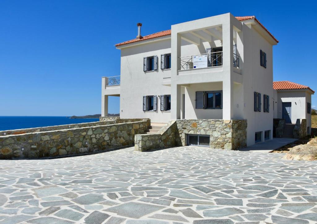 a large white house with a stone driveway at Merabello Villas Karystos in Karistos