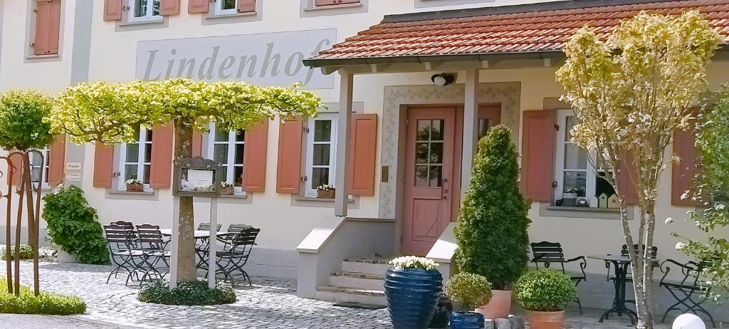 um edifício com uma porta rosa, uma mesa e cadeiras em Hotel garni Lindenhof im Steigerwald em Oberaurach