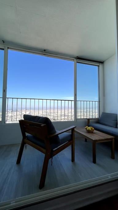Cette chambre comprend une chaise, une table et une grande fenêtre. dans l'établissement Superbe Appartement 2 chambres avec vue sur la mer et la montagne, à Marseille