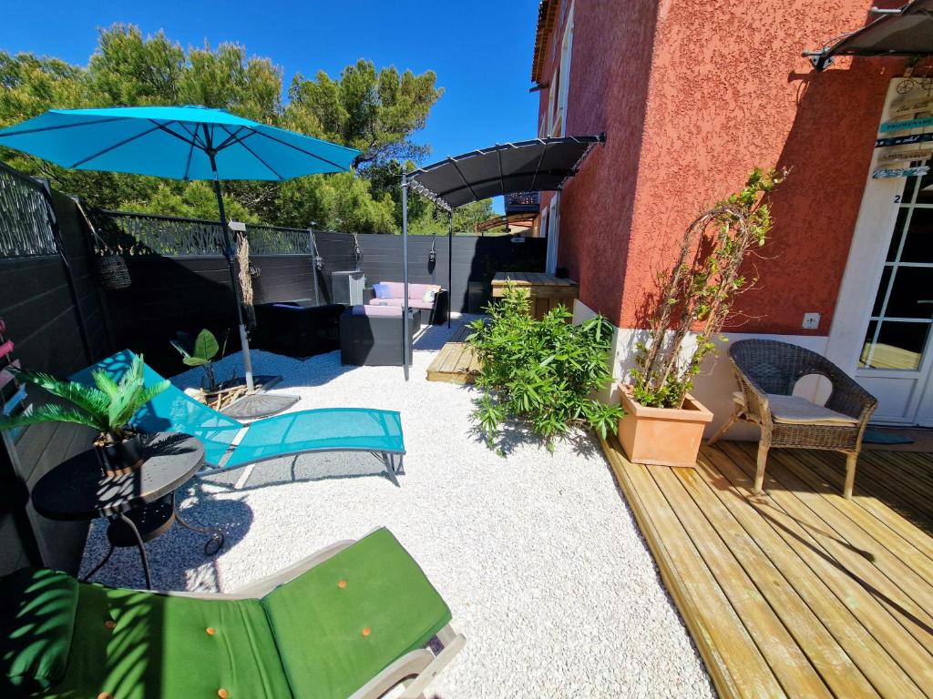 eine Terrasse mit Stühlen, einem Sonnenschirm und einem Tisch in der Unterkunft L'Instant Mer - Bord de Mer - Studio avec grand jardin à La Capte in Hyères