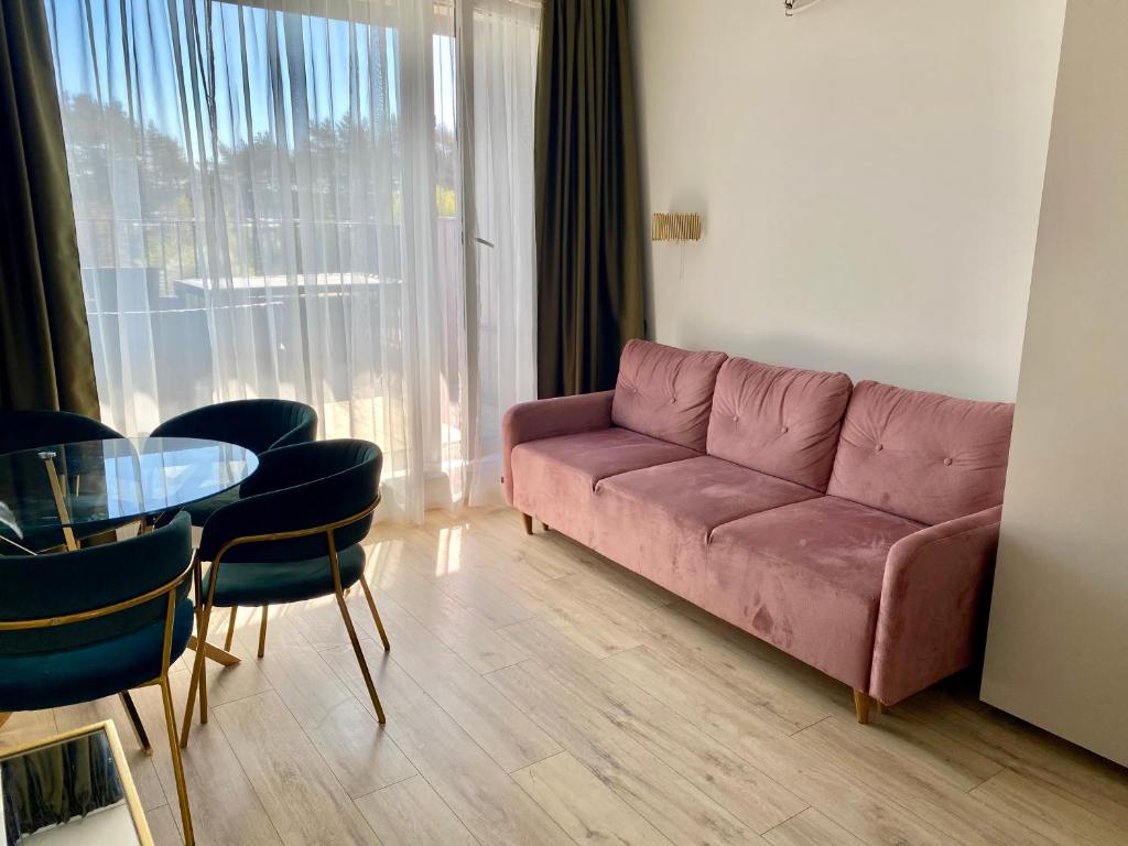 salon z różową kanapą i stołem w obiekcie Kunigiškiai Mano Jūra2 apartamentai w Połądze
