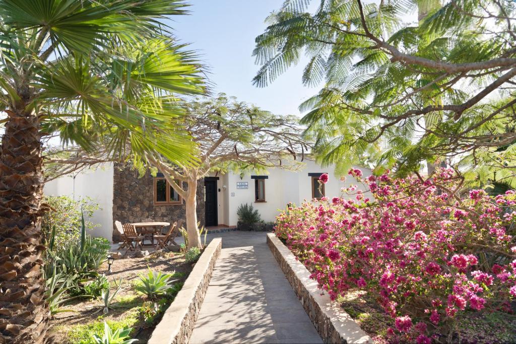een tuin met roze bloemen en palmbomen bij Villa Helda - Private Bedroom in a Shared Villa of 4 bedroom in Villaverde