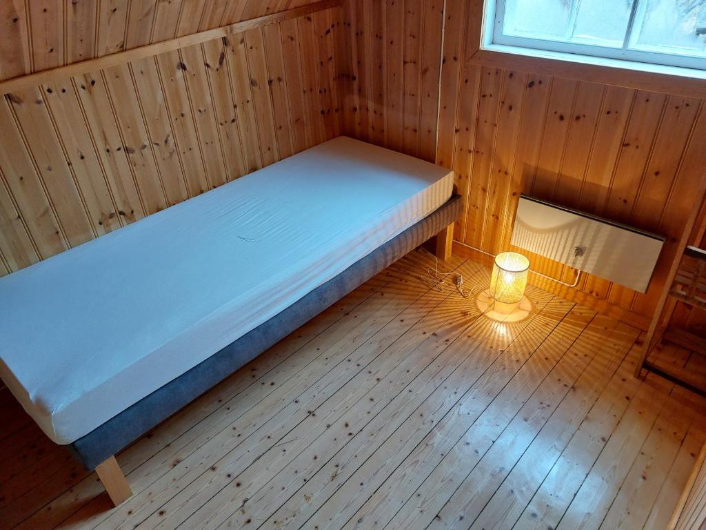 a bed in a wooden room with a light on the floor at Elanden rust in Edebäck