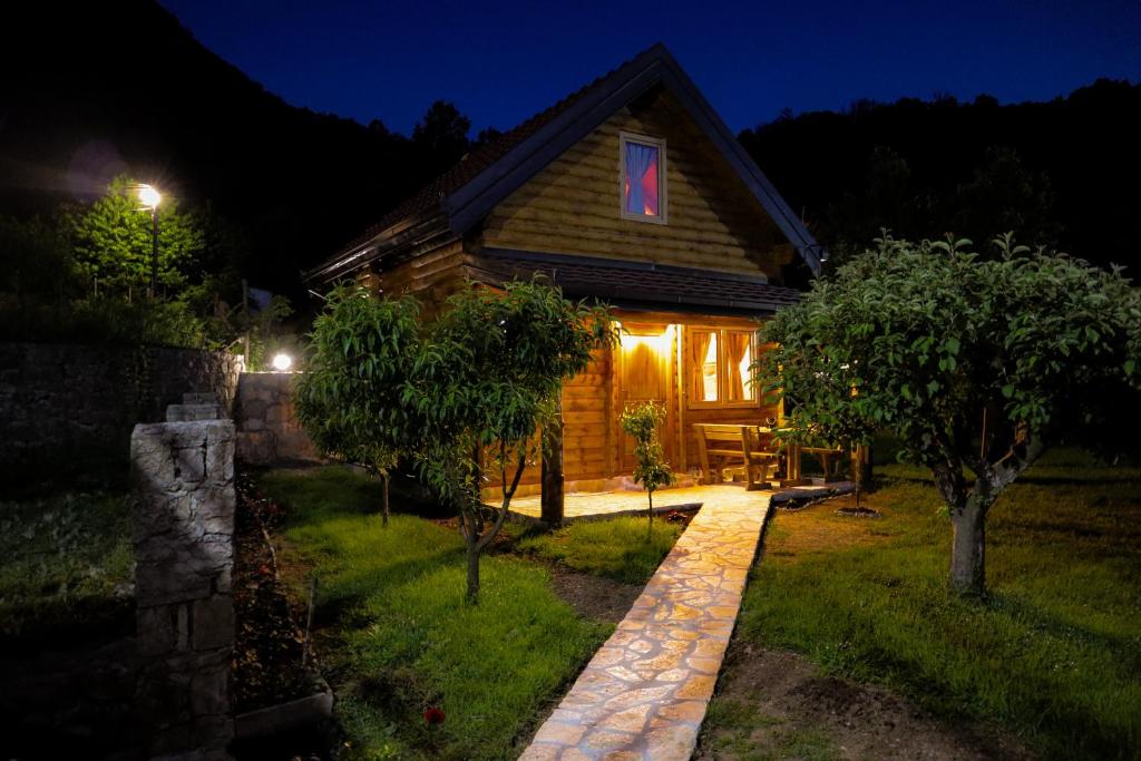 eine Blockhütte in der Nacht mit einem rosa Fenster in der Unterkunft Green Field Apartments in Virpazar