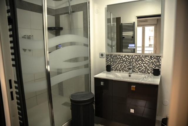 Un baño con ducha de cristal y lavabo. en F2 Vaires sur marne, en Vaires-sur-Marne