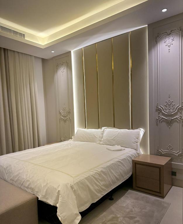 a bedroom with a large white bed and a table at fin apartment C6 in Riyadh