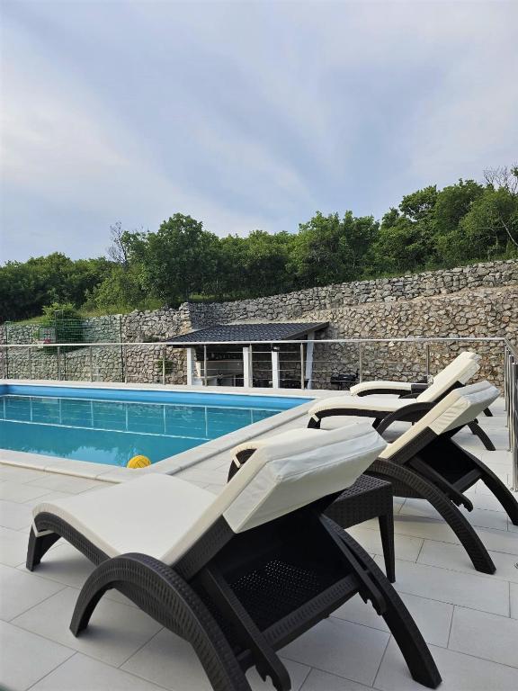 a row of lounge chairs next to a swimming pool at Holiday House Nirvana in Bakarac