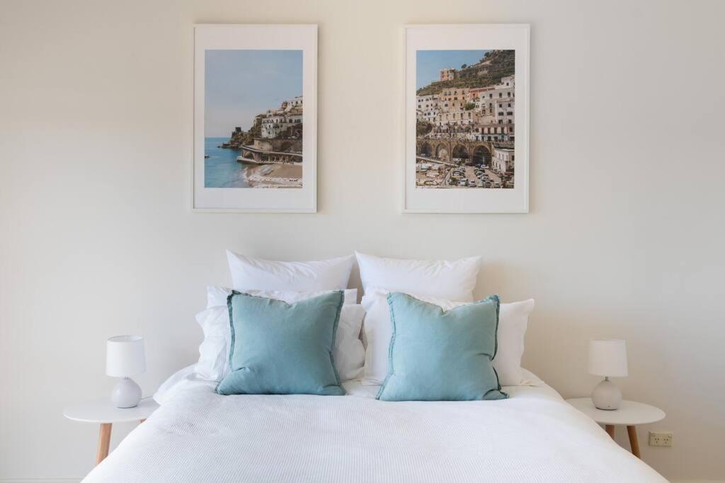 a white bed with two blue pillows on it at Casa Sorrento in Sorrento