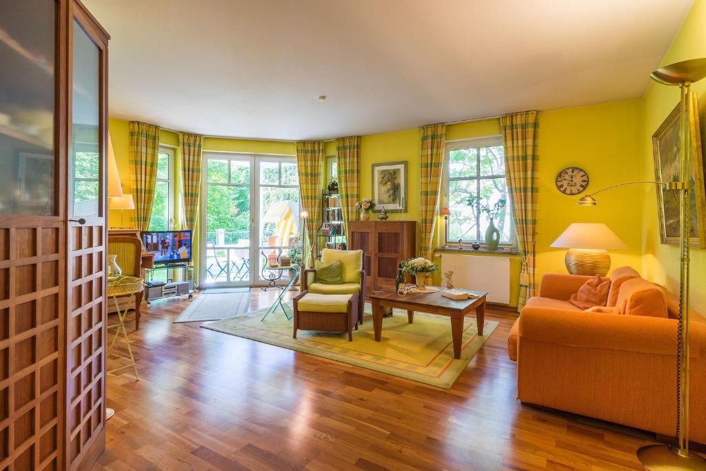 ein Wohnzimmer mit gelben Wänden, einem Sofa und einem Tisch in der Unterkunft Villa Charlotte App.13 in Heringsdorf