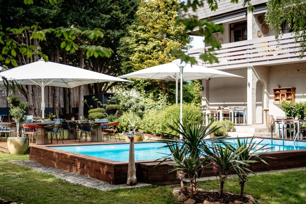 een zwembad met parasols, tafels en stoelen bij Hotel Drahteselböck in Rust