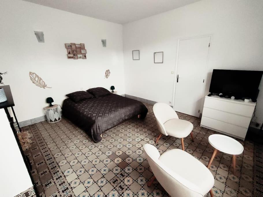 ein Schlafzimmer mit einem Bett und zwei weißen Stühlen in der Unterkunft La ferme des sorciers in Agnez-lès-Duisans