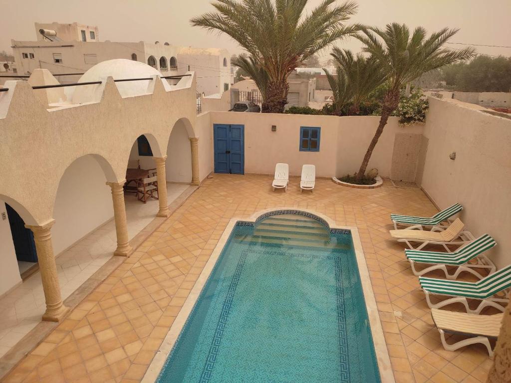 una piscina en un patio con sillas y una casa en Villa Ulysse Djerba en Midoun