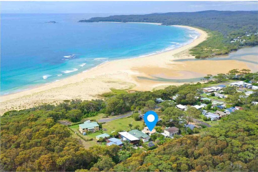eine Luftaufnahme eines Strandes mit einem blauen Schild in der Unterkunft SeaRoos by the Seashore Beach Cottage in Durras