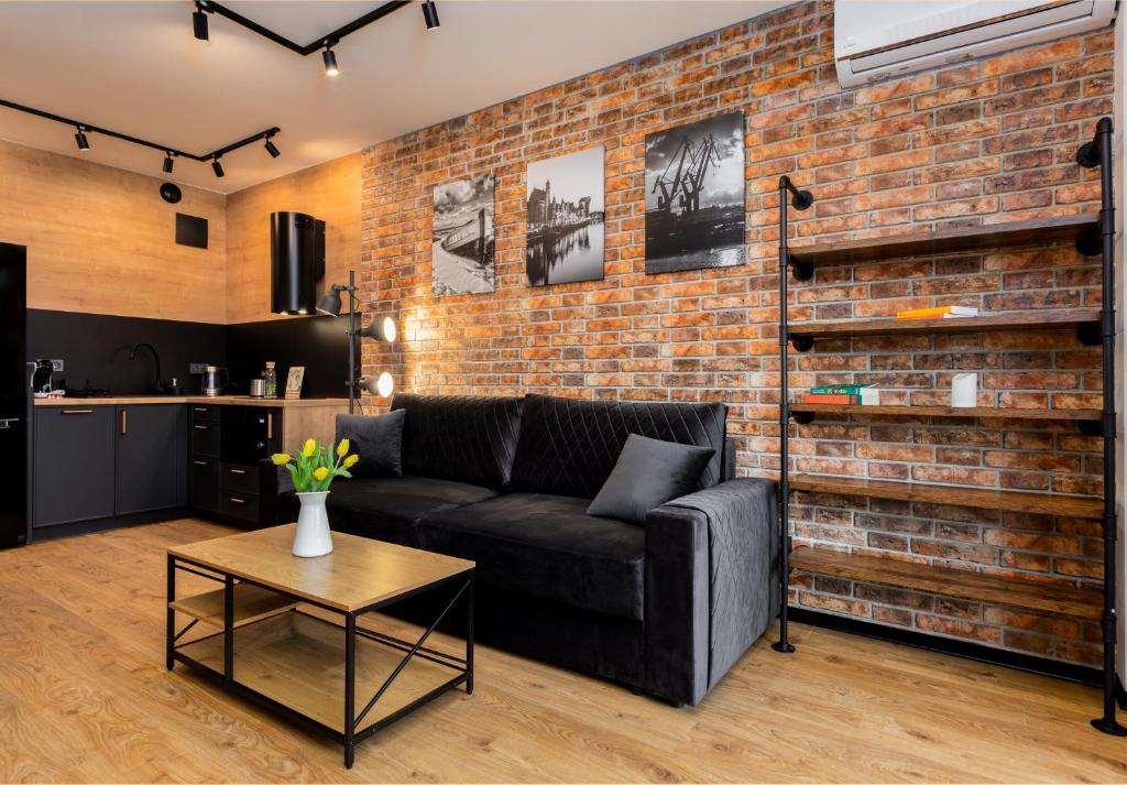 a living room with a couch and a brick wall at STAR Apartments Gdańsk - Gym & Sauna in Gdańsk
