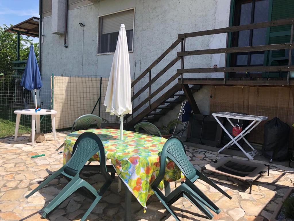 een tafel met een paraplu en twee stoelen en een tafel bij Mini appartamento in campagna in Castagneto Carducci