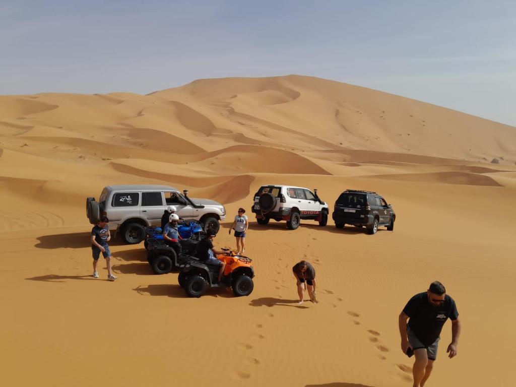 a group of people standing in the desert at Mustapha Camp Merzouga in Merzouga