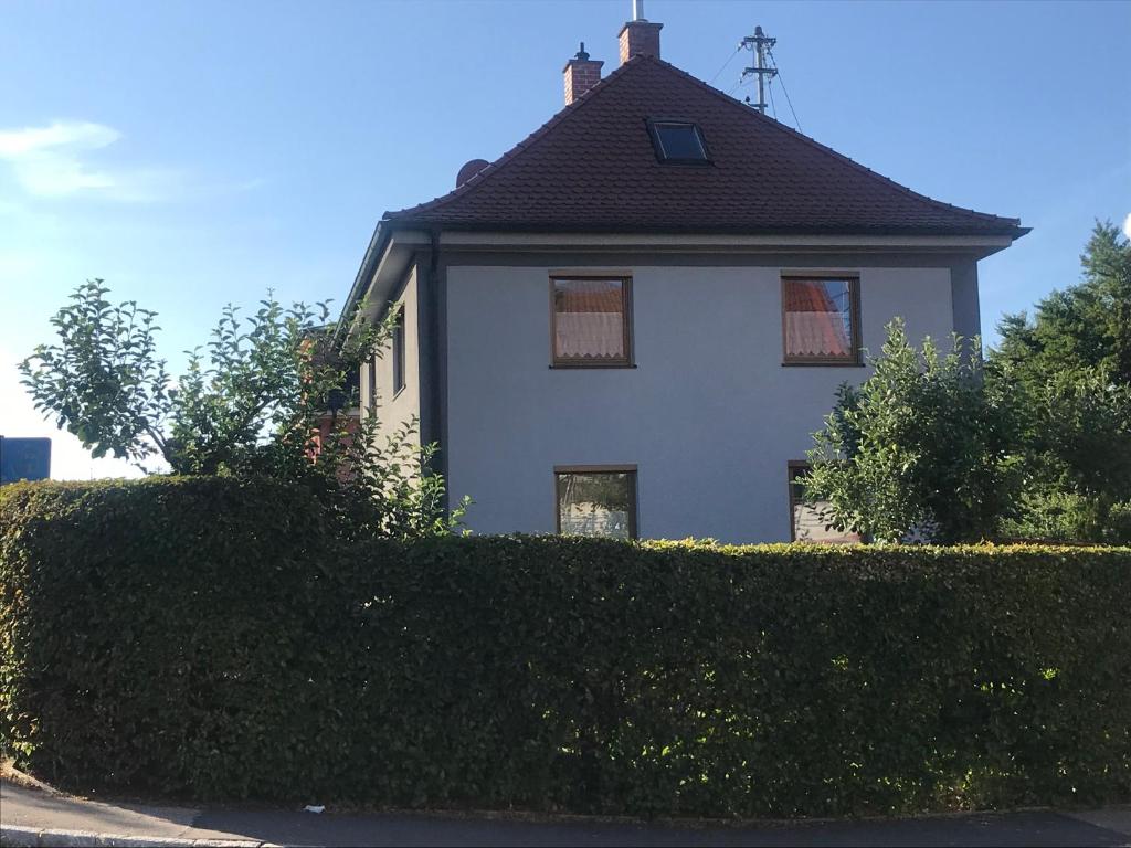 een wit huis met een zwart dak achter een heg bij Gästehaus Nicole in Burgau