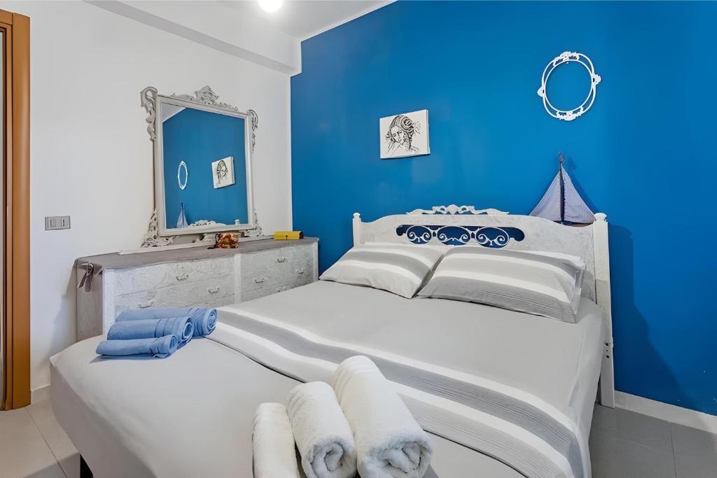 Dormitorio azul con cama blanca y espejo en Casa Vacanza Violisa, en Alcamo Marina