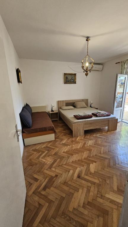 a bedroom with a bed and a wooden floor at Radenović, soba in Budva