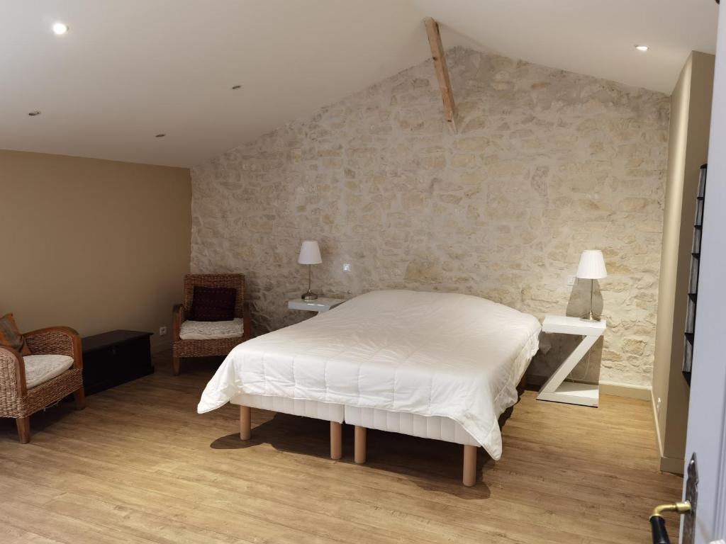 a bedroom with a white bed and a stone wall at Maison avec jardin in Pernes-les-Fontaines