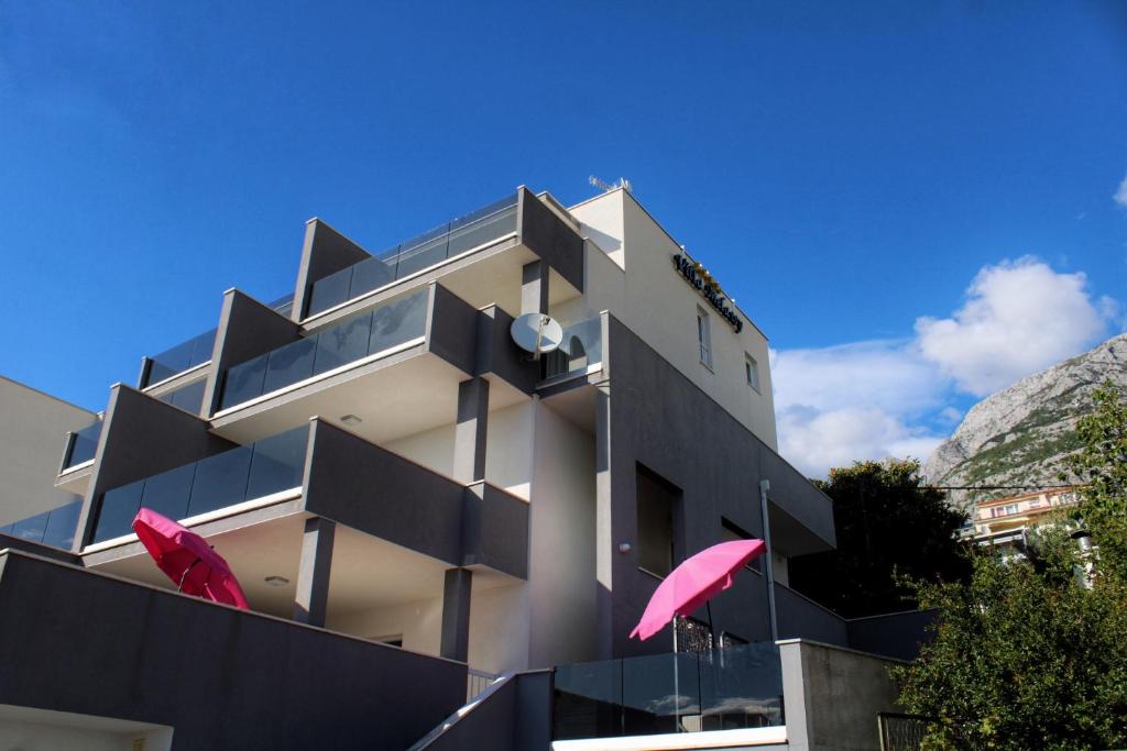 a building with two pink umbrellas in front of it at Villa Melassy in Makarska
