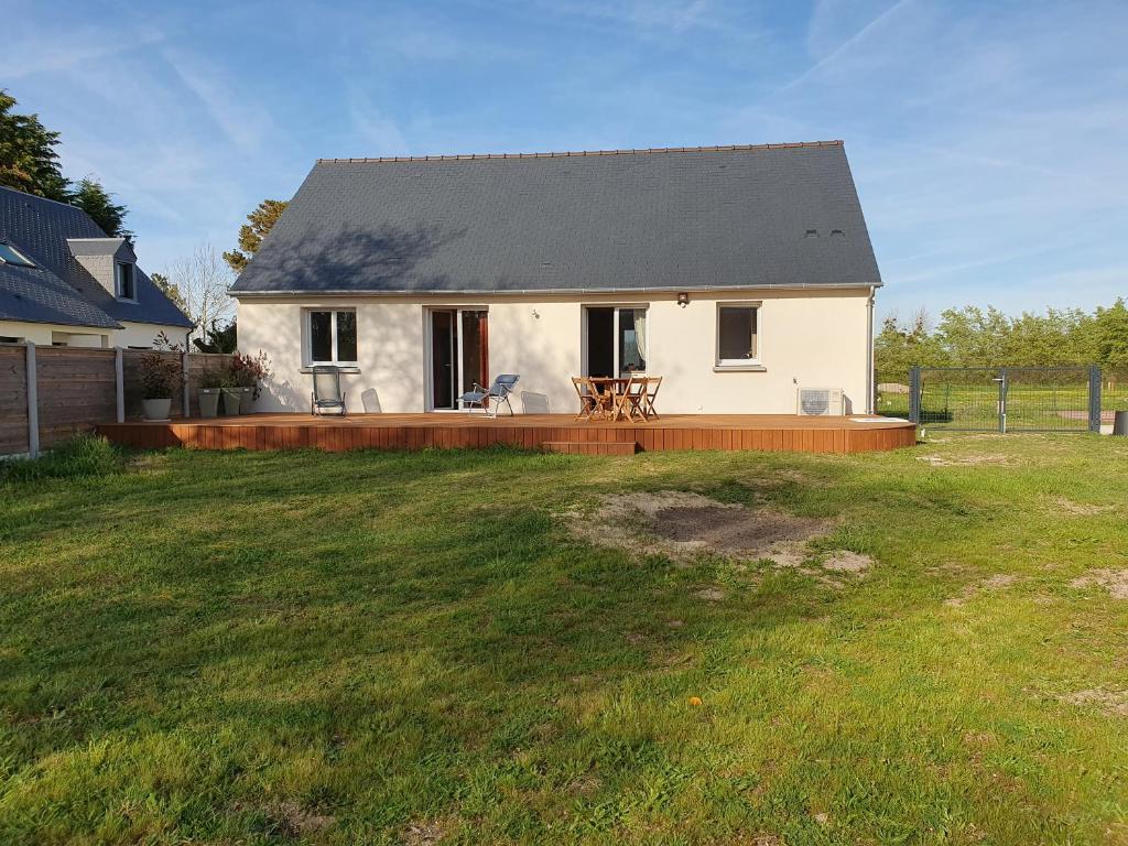 une maison blanche avec une terrasse dans une cour dans l'établissement Location les Bruyères, à Saint-Germain-sur-Ay