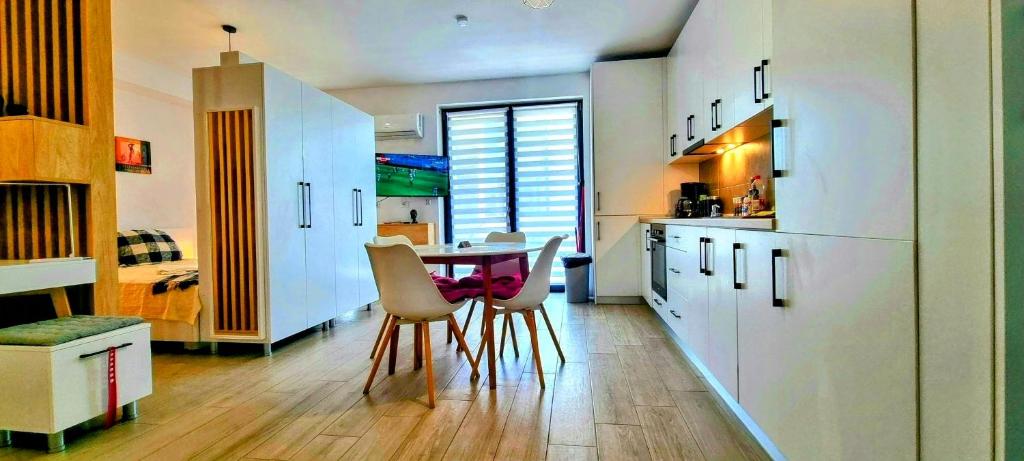 eine Küche mit weißen Schränken sowie einem Tisch und Stühlen in der Unterkunft ATENEO - Studio DeLuxe Modern Apartment, Big Balcony, Plus Parking in Timişoara
