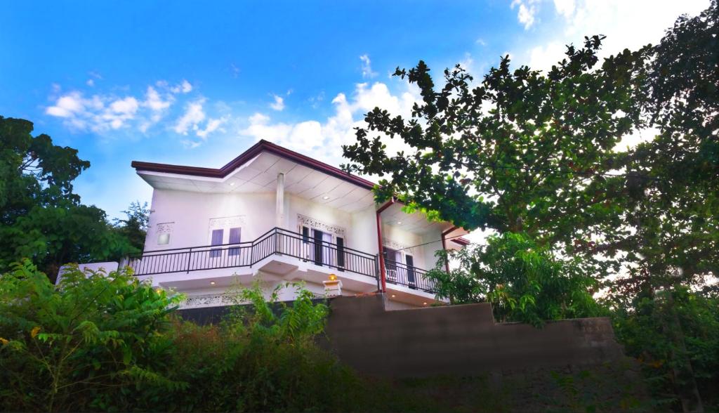 a white house with a balcony and trees at Ananthaya-the infinity in Kalutara