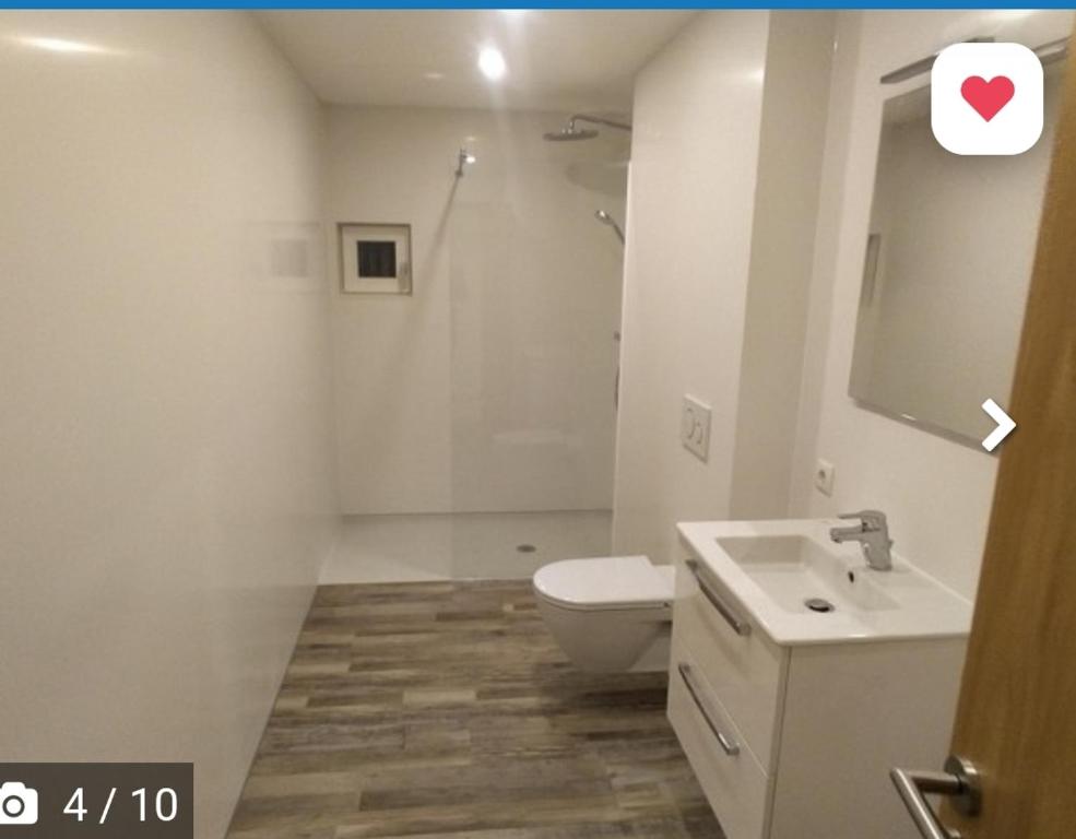 La salle de bains blanche est pourvue de toilettes et d'un lavabo. dans l'établissement Haus Abendrot, à Dornbirn