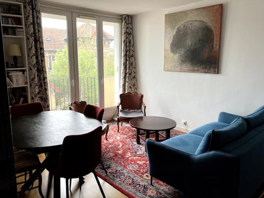 un salon avec un canapé bleu et une table dans l'établissement Charmant appartement au calme, à Villemomble