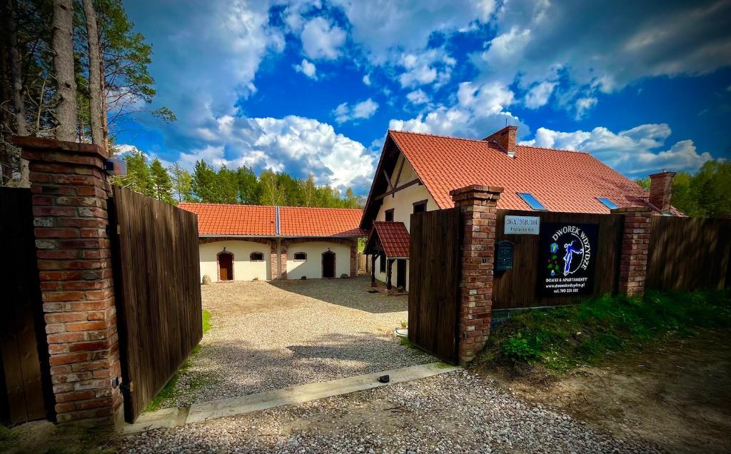 ein Haus mit einem Holzzaun davor in der Unterkunft Dworek Wdzydze in Przytarnia