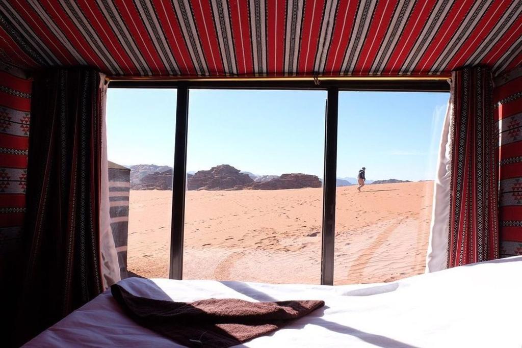a bedroom with a view of the desert from a window at Wadi Rum Trip in Wadi Rum