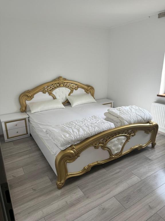 Cama dorada en un dormitorio con suelo de madera en Schöne Wohnung in Satrup en Satrup