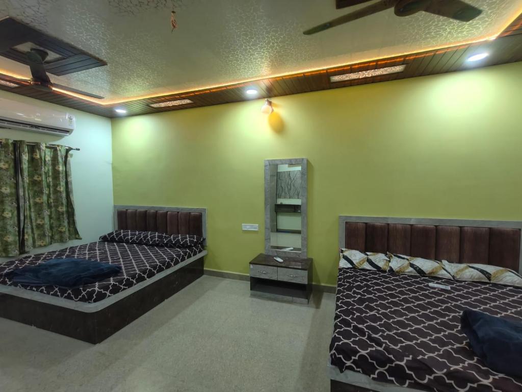 two beds in a room with green walls at Mahakal Homestay in Ujjain