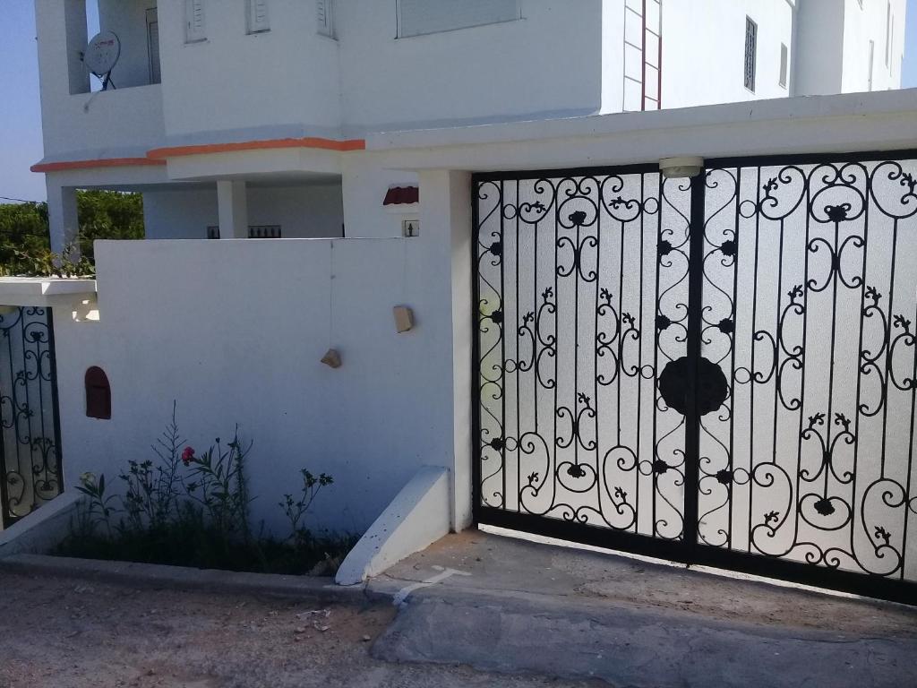 brama przed białym budynkiem w obiekcie maison à louer les grottes Bizerte Tunisie w mieście Dar el Koudia