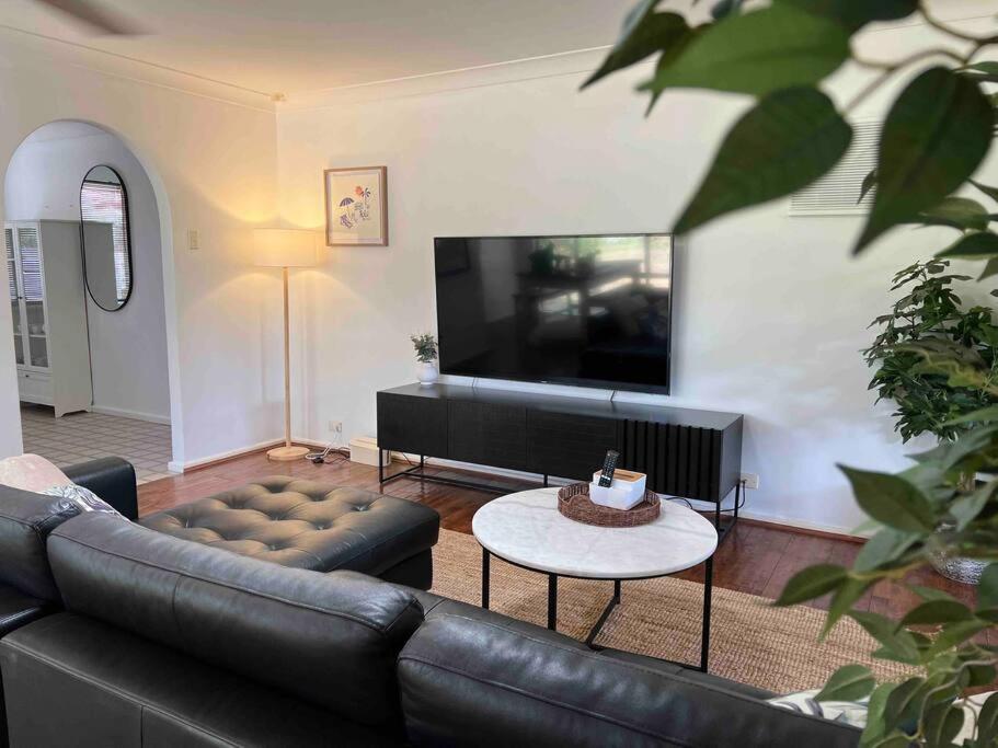 sala de estar con sofá de cuero y TV en Humble & Homely, en Rockingham