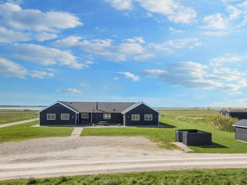 a black house in the middle of a field at 22 person holiday home in Harbo re in Harboør
