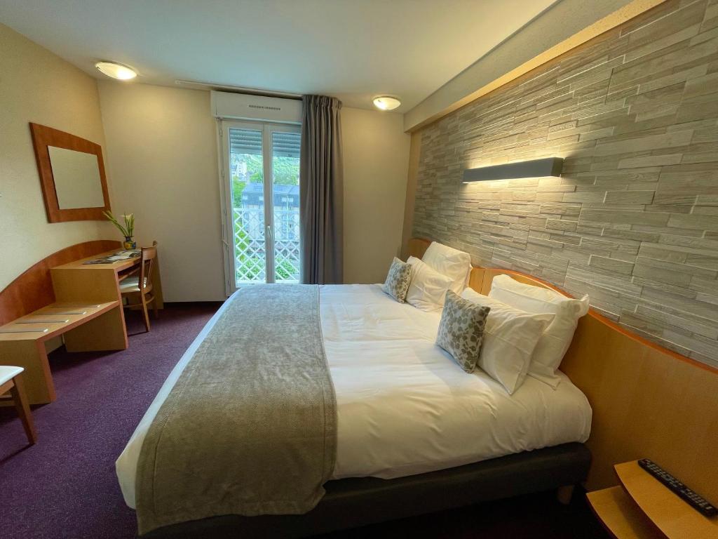 une chambre d'hôtel avec un lit et un mur en briques dans l'établissement Hôtel Saint Georges, à Lourdes