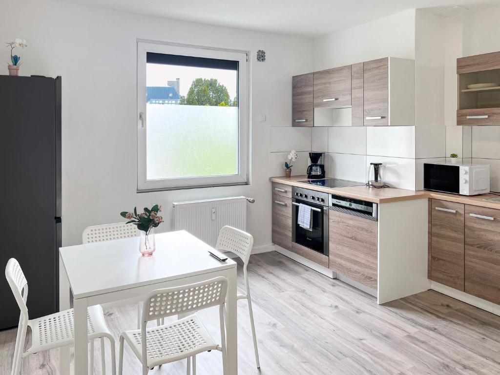 een keuken met een tafel en een witte tafel en stoelen bij T&K Apartments - Krefeld Zentrum - 1 and 2 room Apartment 20min to Fair DUS in Krefeld