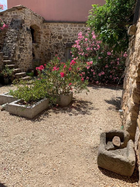 un jardin avec des fleurs roses et des rochers dans l'établissement Mas Héritage, à Rosières