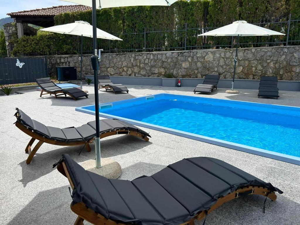 a swimming pool with two lounge chairs and an umbrella at Villa Fantasea in Opric