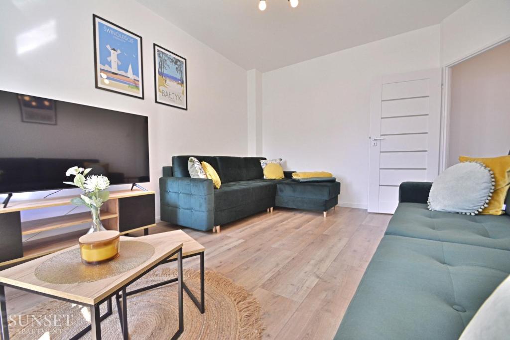 - un salon avec deux canapés bleus et une télévision dans l'établissement Sunset Apartments - Monte Cassino 6 - przestronny apartament przy deptaku, à Świnoujście