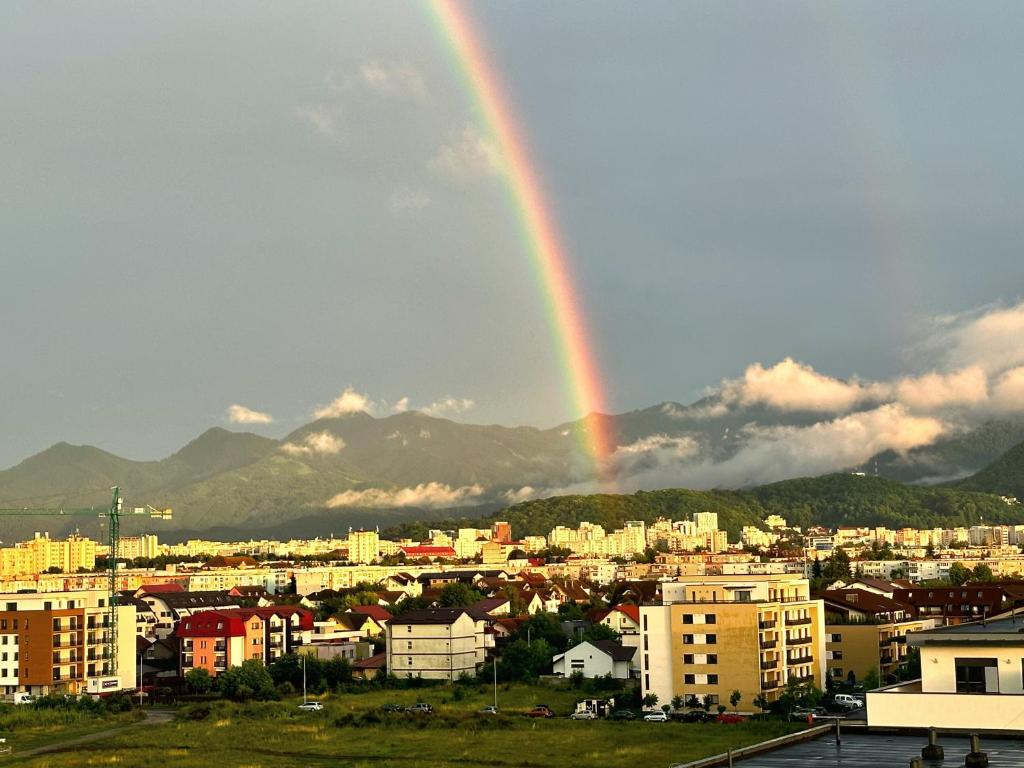 Un arcobaleno nel cielo sopra una città con edifici di KOA - Twin Tower a Braşov