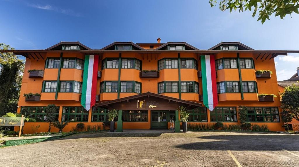 un edificio naranja con banderas en la parte delantera en Hotel Fioreze Origem, en Gramado