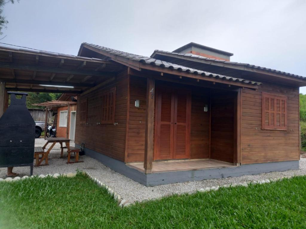 ein kleines Holzgebäude mit einer Veranda und Gras in der Unterkunft Pousada Encantos Da Montanha in Lauro Müller