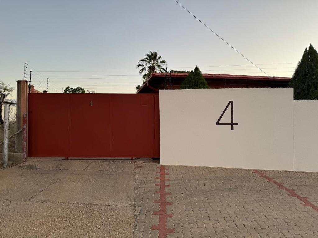 Una pared blanca con el número cuatro. en Ramblers Self-Catering Hostel (No Aircon/No TV/No Pool), en Windhoek