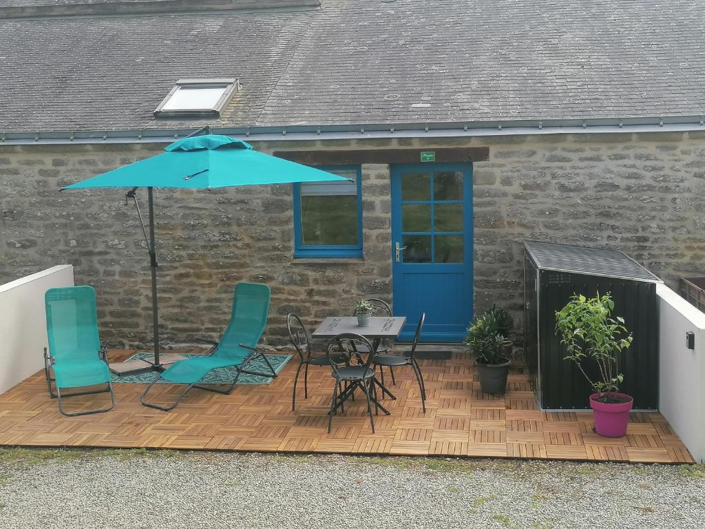 een patio met een tafel en stoelen en een parasol bij Studio Sulniac Golfe du morbihan in Sulniac
