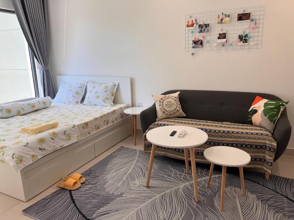 a bedroom with a bed and a couch and tables at Vinhome Grand Park Homestay-Cozy House in Gò Công