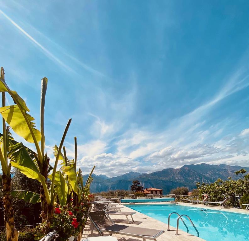 a swimming pool with chairs and mountains in the background at Hotel Ideal in Malcesine