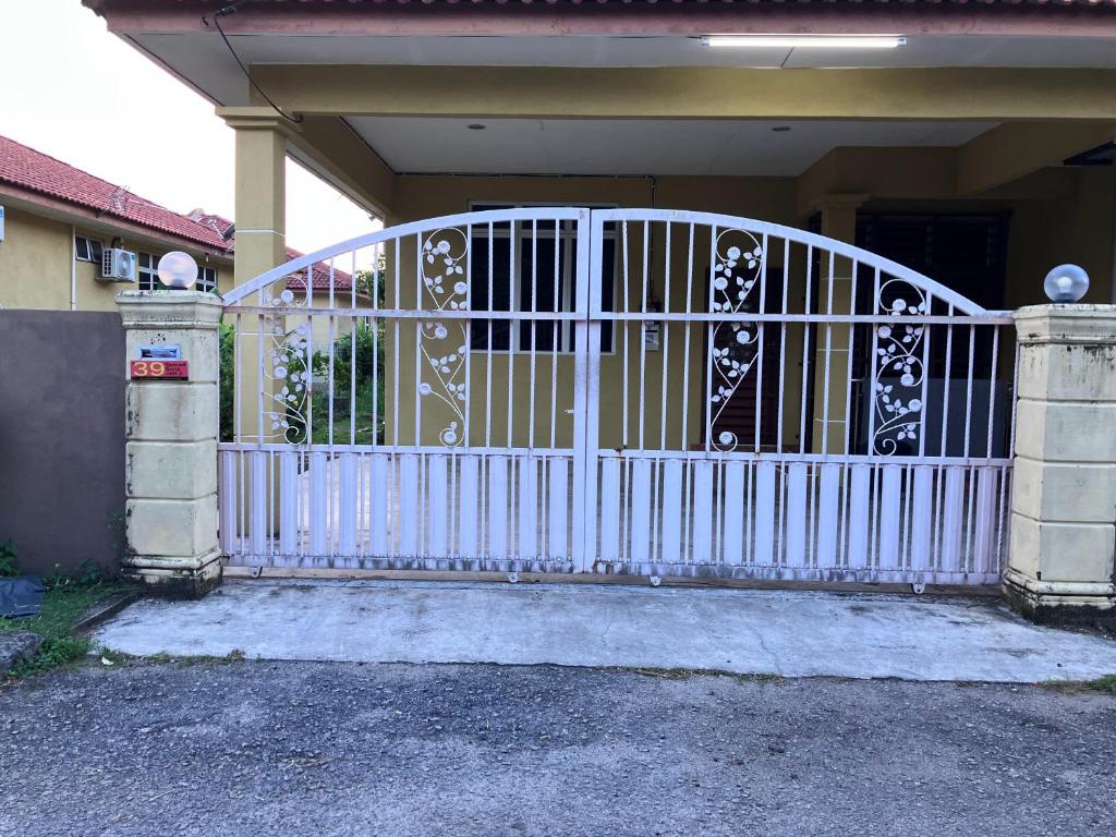 un portail blanc devant une maison dans l'établissement Homestay Al amin 2, à Kampong Sura Tengah